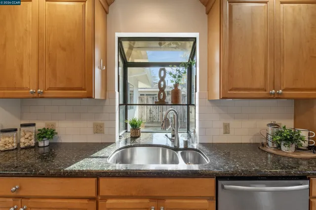 a kitchen with stainless steel appliances granite countertop a potted plant on the counter and cabinets