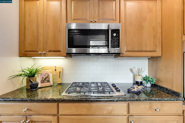 a kitchen with stainless steel appliances granite countertop a stove a sink and a microwave