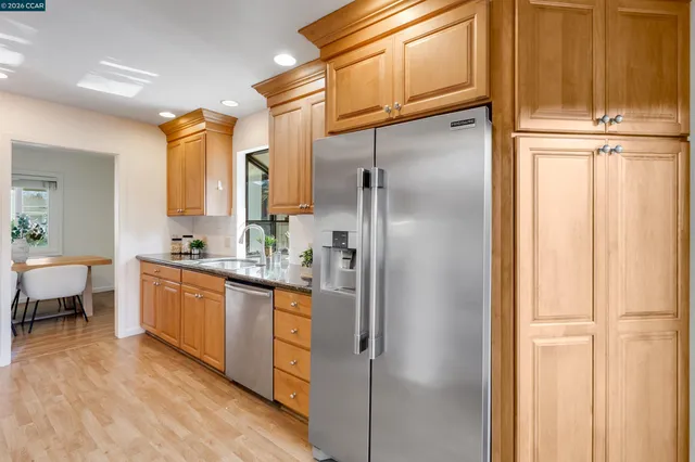 a kitchen with refrigerator and wooden floor