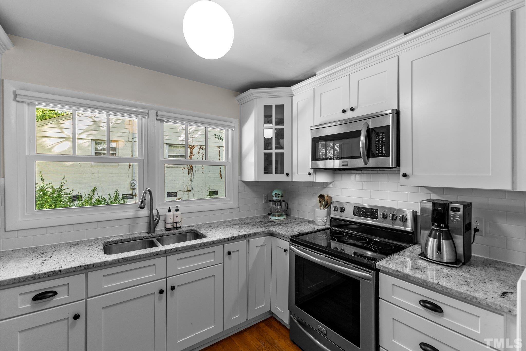 4912 Latimer Road Raleigh, NC 27609 - Photo 8 of 35 a kitchen with stainless steel appliances granite countertop white cabinets a sink and a window
