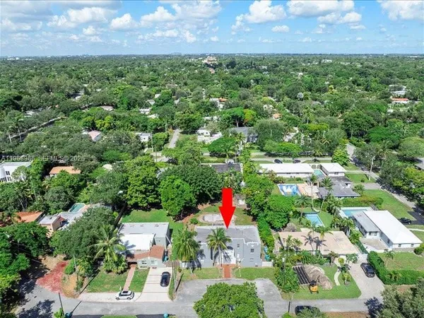 an aerial view of residential houses with outdoor space and trees all around