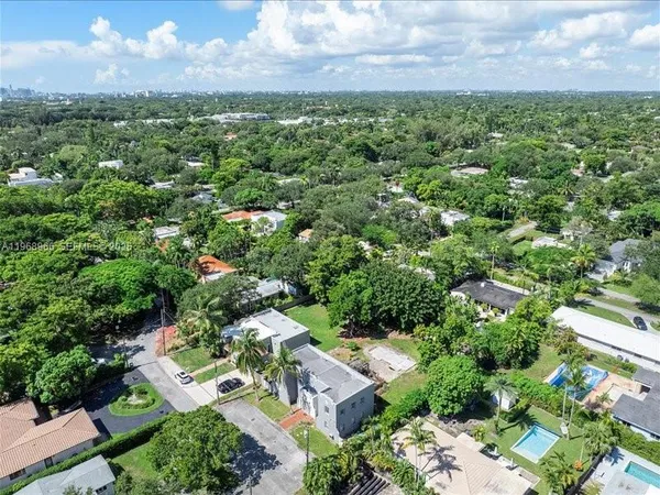 an aerial view of residential houses with outdoor space and trees