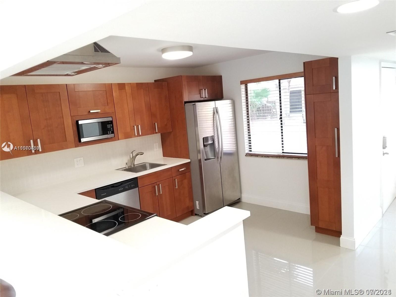 a kitchen with stainless steel appliances a sink a stove a refrigerator a microwave a counter top and cabinets