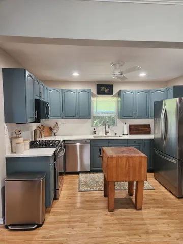 a kitchen with stainless steel appliances granite countertop a table chairs sink refrigerator and microwave