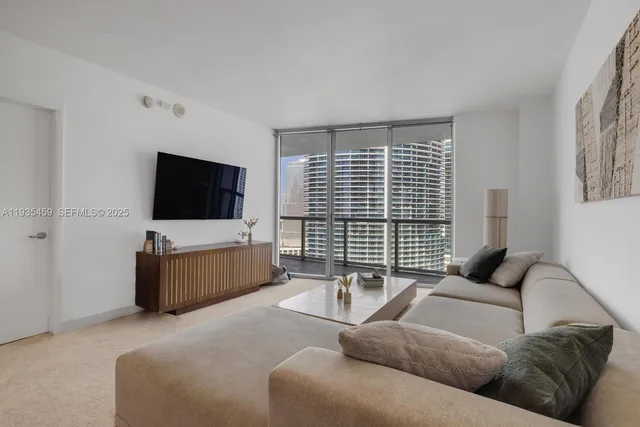 a living room with furniture a chandelier and a floor to ceiling window