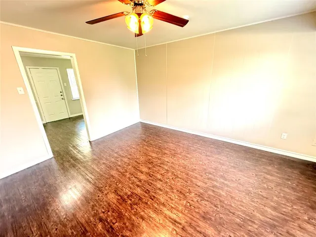 an empty room with wooden floor and fan
