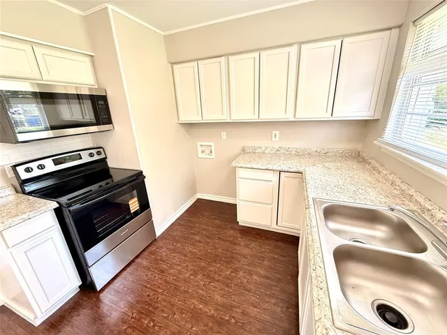 a kitchen with granite countertop a stove a sink and a microwave
