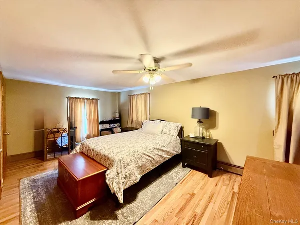 a spacious bedroom with a bed and dresser with wooden floor