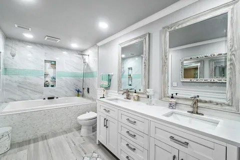 a bathroom with a double vanity sink toilet mirror and bathtub