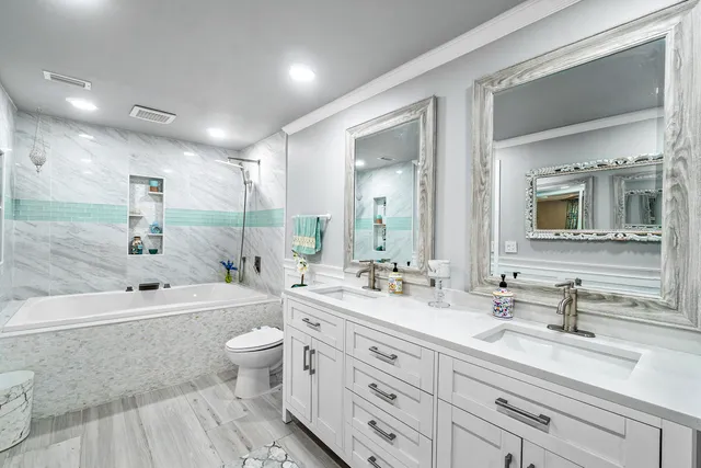 a bathroom with a double vanity sink toilet mirror and bathtub