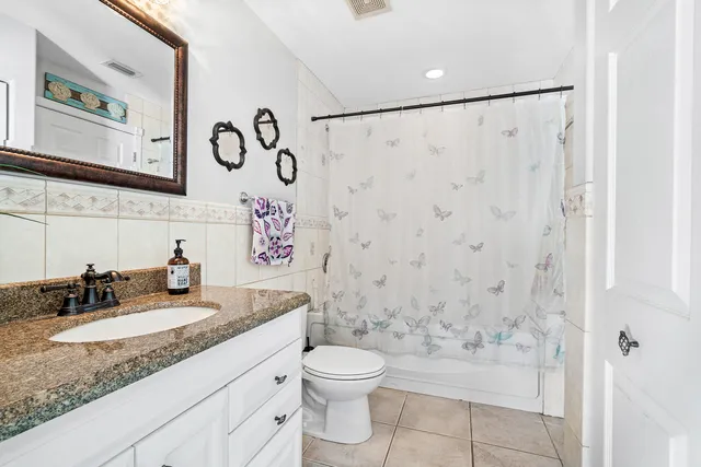 a bathroom with a granite countertop sink a toilet and a shower