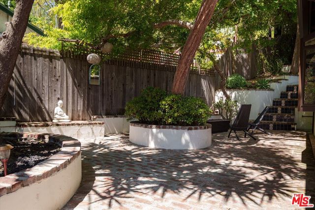 a view of a backyard with potted plants and large trees