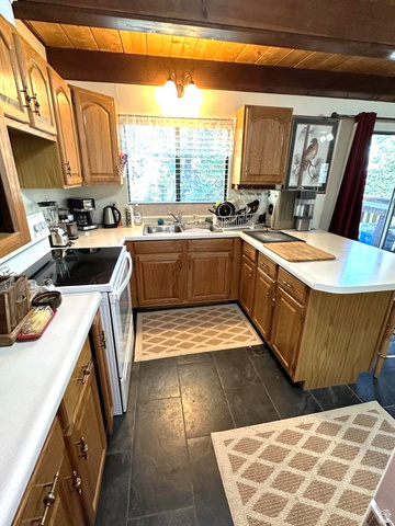 1456 Navajo Road Coalville, UT 84017 - Photo 13 of 55 Kitchen featuring white electric range, a peninsula, light countertops, wood finish cabinets, and a wooden ceiling with exposed beams