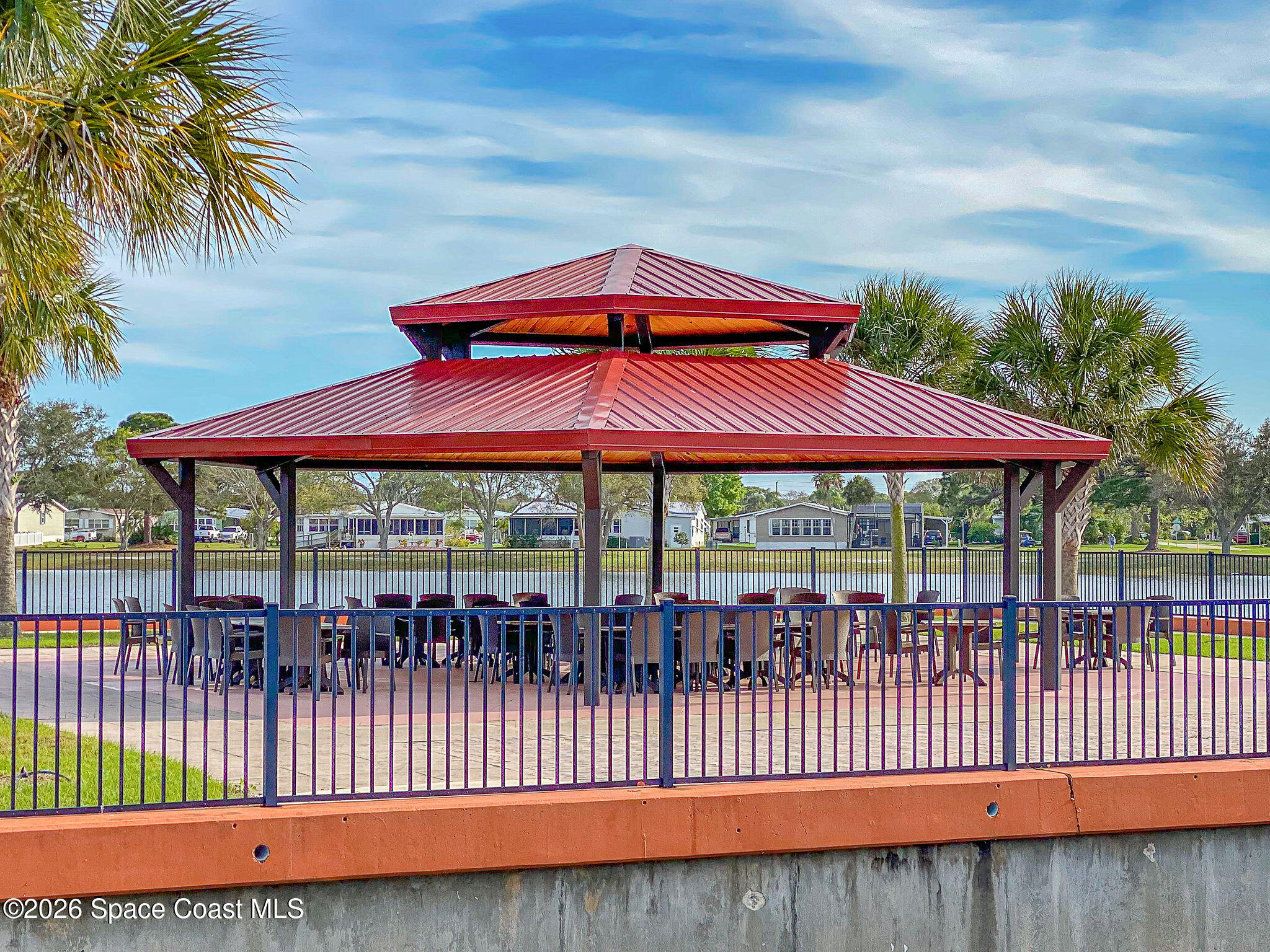 811 Silverthorn Court Barefoot Bay, FL 32976 - Photo 73 of 74 a view of a deck with a table and chairs under an umbrella with wooden fence