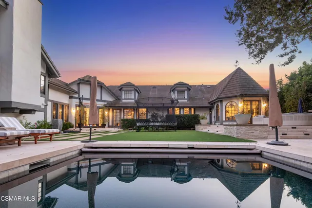 a view of a big house with a yard and table and chairs under an umbrella
