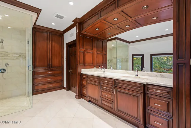 a bathroom with a double vanity sink and mirror with shower