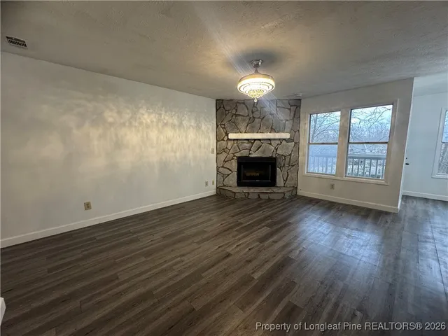 an empty room with wooden floor fireplace and windows