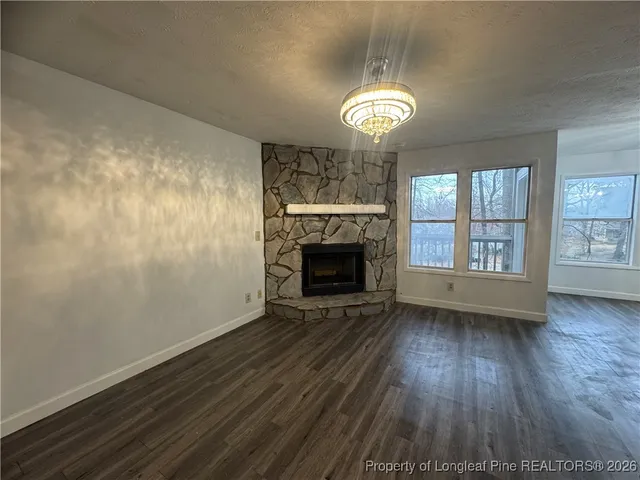 an empty room with wooden floor a fireplace and windows