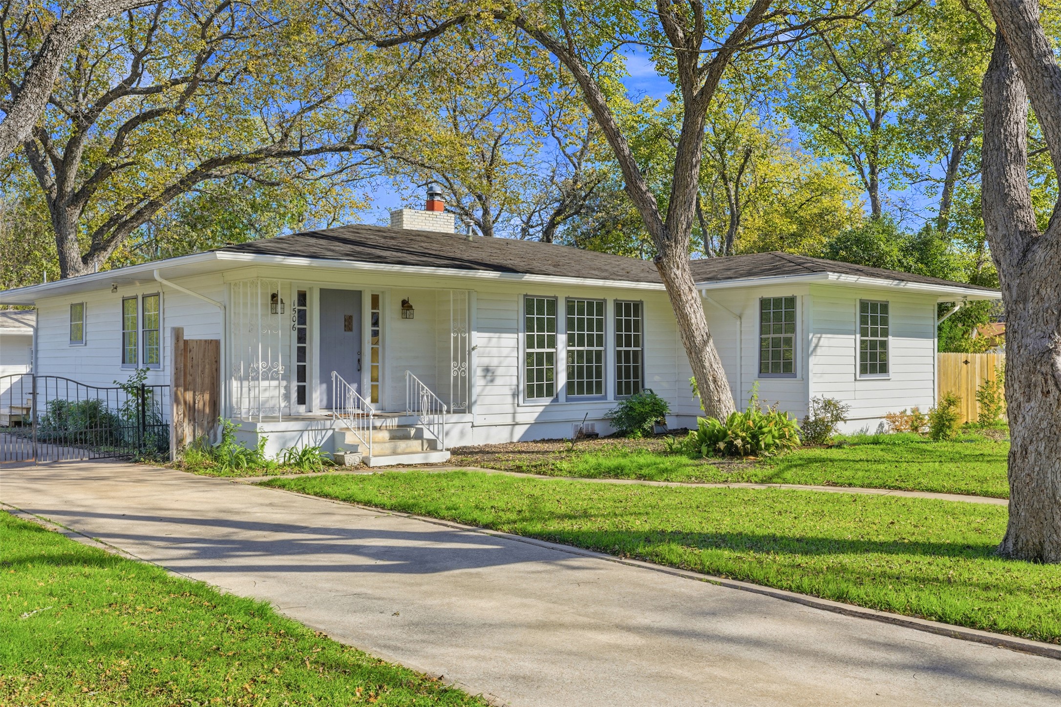 Mid Century Ranch-style house featuring a chimney and covered porch and spacious yard with trees