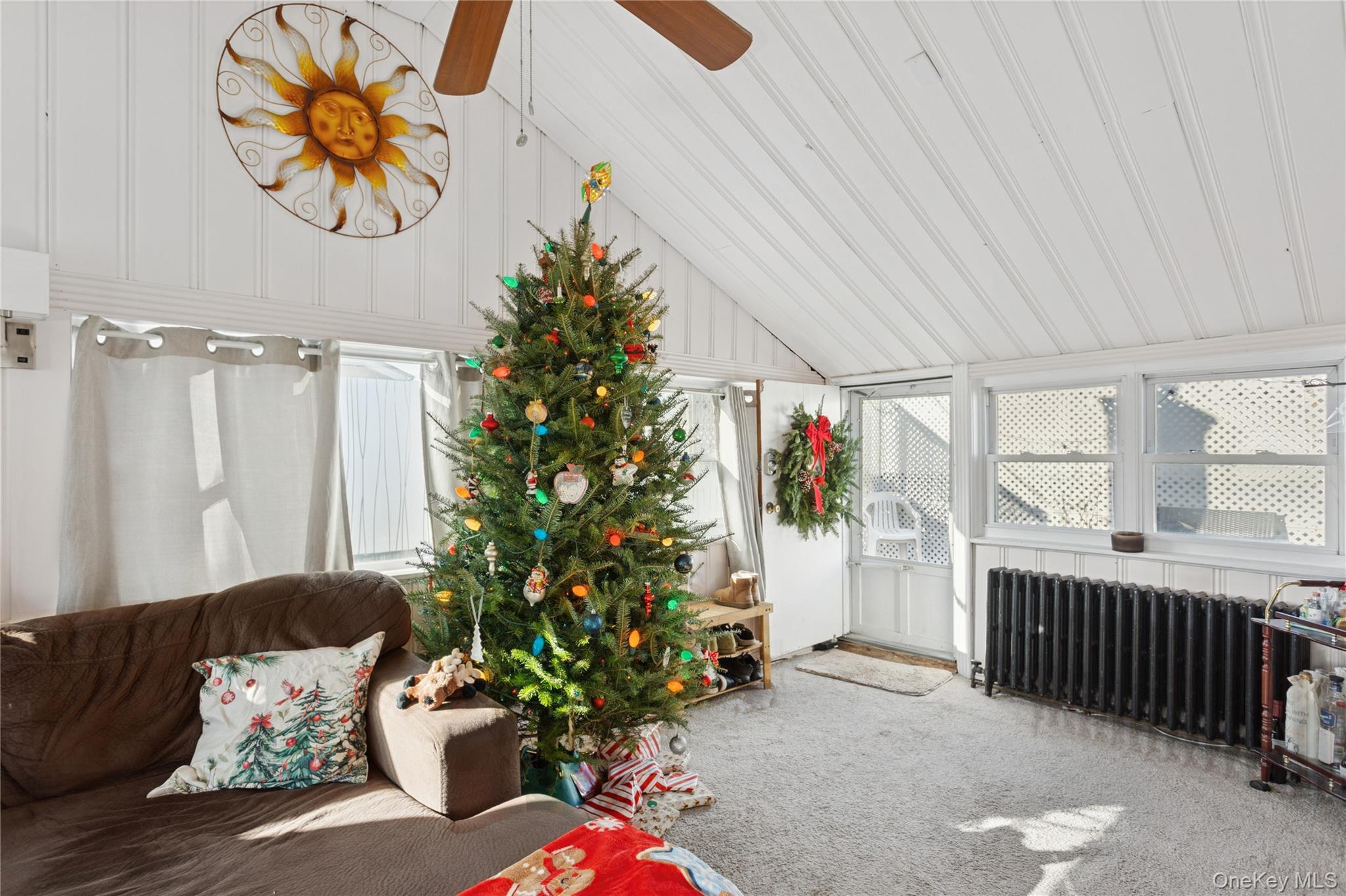 107 Pacific Boulevard Long Beach, NY 11561 - Photo 11 of 23 Sunroom / solarium featuring carpet floors, radiator, a decorative wall, and lofted ceiling