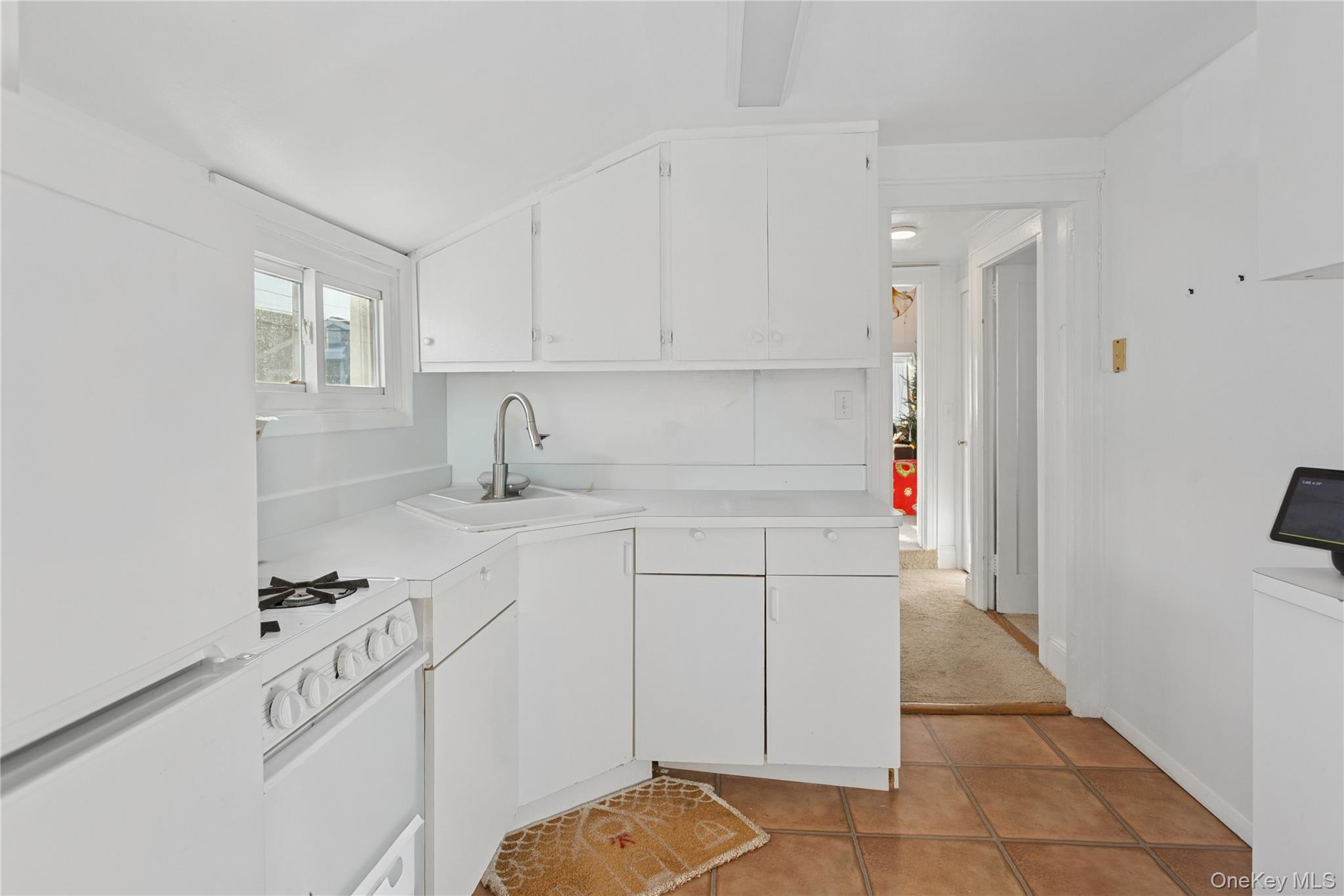 107 Pacific Boulevard Long Beach, NY 11561 - Photo 14 of 23 Kitchen with white appliances, white cabinets, light countertops, and light tile patterned floors