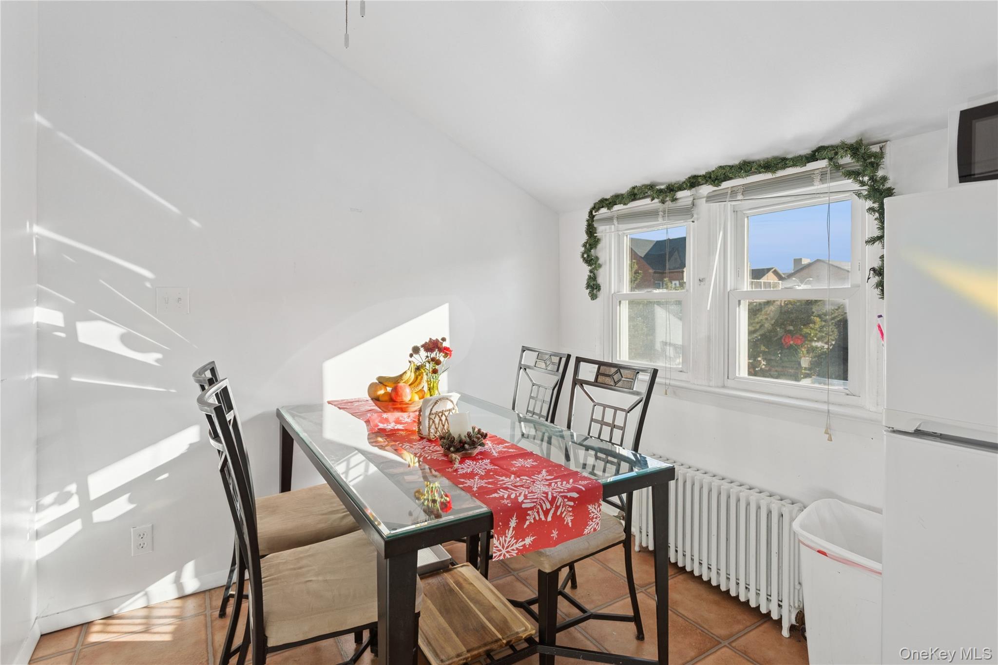 107 Pacific Boulevard Long Beach, NY 11561 - Photo 15 of 23 Tiled dining room featuring radiator heating unit and lofted ceiling