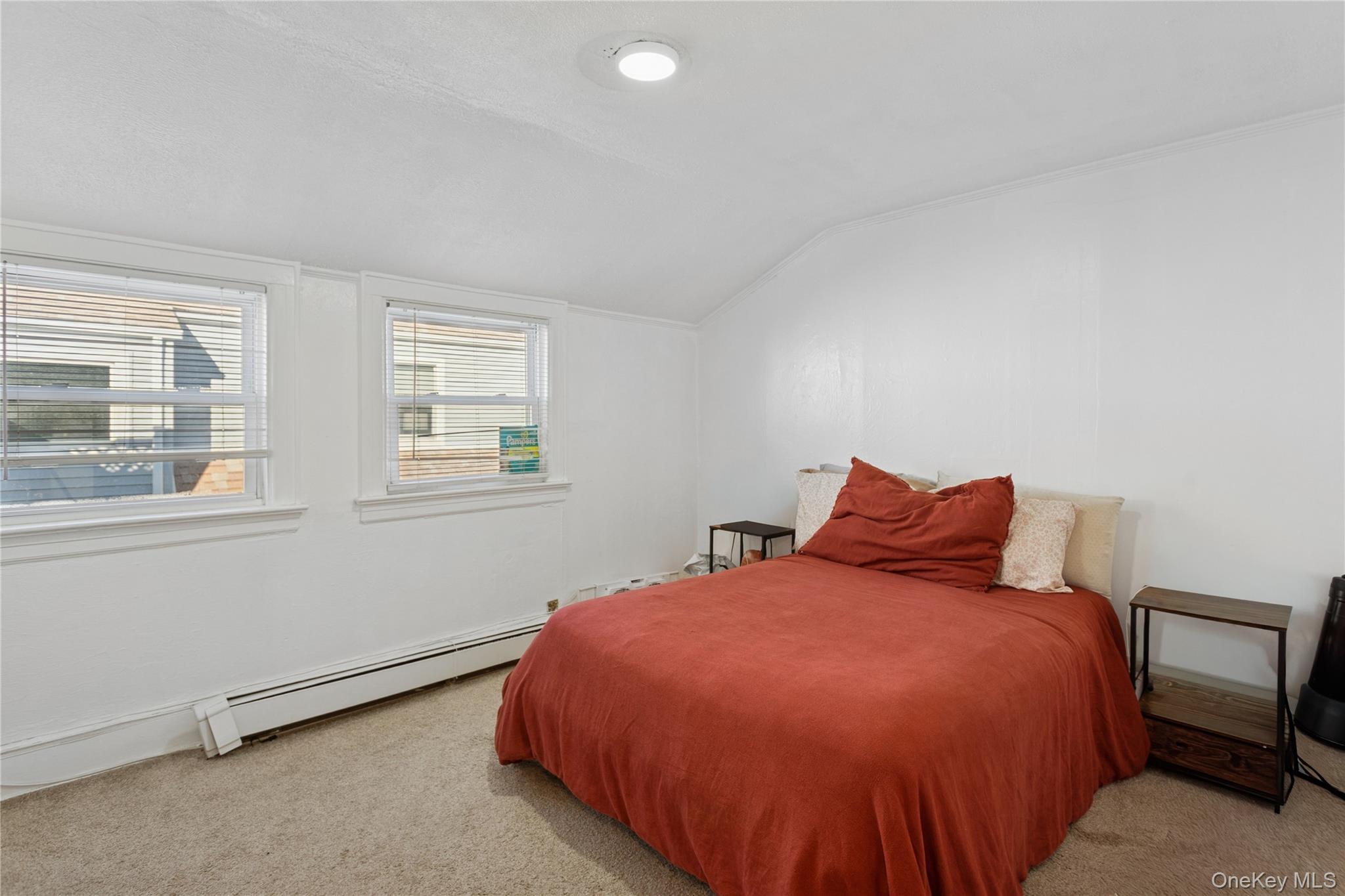 107 Pacific Boulevard Long Beach, NY 11561 - Photo 17 of 23 Bedroom featuring a baseboard heating unit, light colored carpet, and lofted ceiling