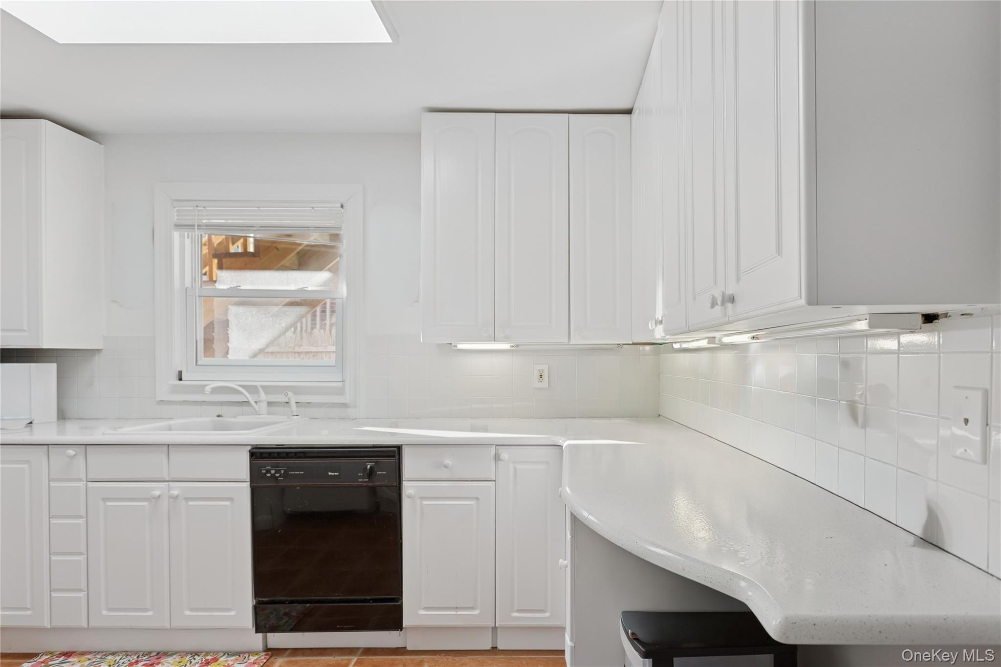 107 Pacific Boulevard Long Beach, NY 11561 - Photo 6 of 23 Kitchen with white cabinets, tasteful backsplash, black dishwasher, and light stone countertops