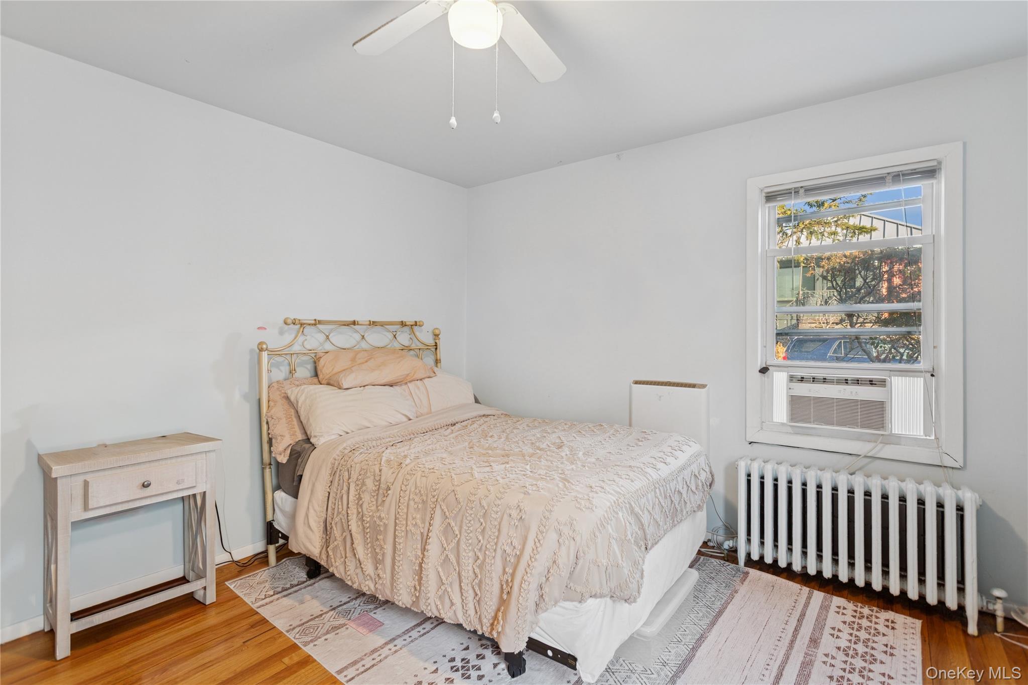 107 Pacific Boulevard Long Beach, NY 11561 - Photo 8 of 23 Bedroom with radiator, wood finished floors, a ceiling fan, and cooling unit