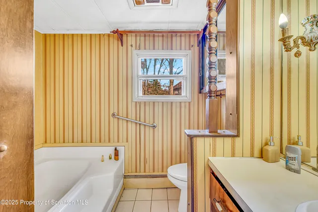 a spacious bedroom with a bed and a flat tv screen on dresser