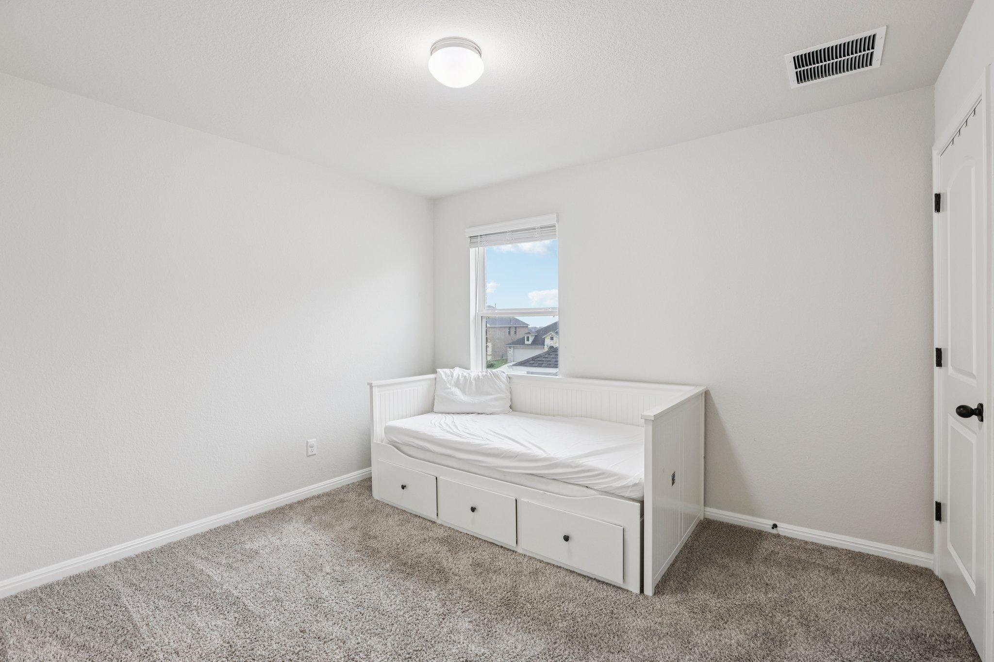 204 Swinging H Lane Georgetown, TX 78633 - Photo 27 of 39 Bright room with light gray walls, gray carpet, and a window with a view of rooftops and sky