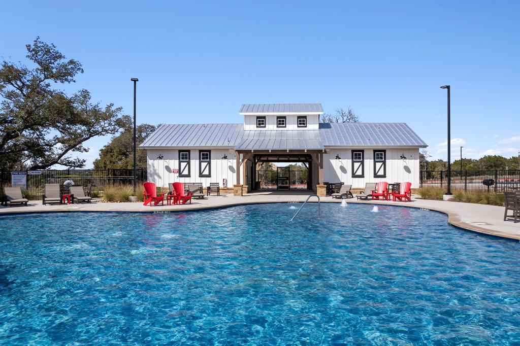 204 Swinging H Lane Georgetown, TX 78633 - Photo 38 of 39 Inviting swimming pool area featuring a white building with a metal roof, lounge chairs, and ample patio space for relaxation