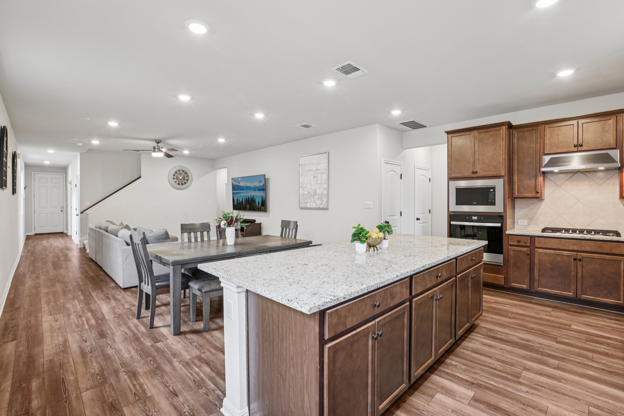 204 Swinging H Lane Georgetown, TX 78633 - Photo 7 of 39 The open-concept living space features wood-style flooring throughout, a kitchen with dark wood cabinetry, a built-in oven and microwave, and a gas cooktop with a stainless steel range hood
