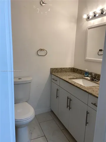 a bathroom with a granite countertop toilet and a sink