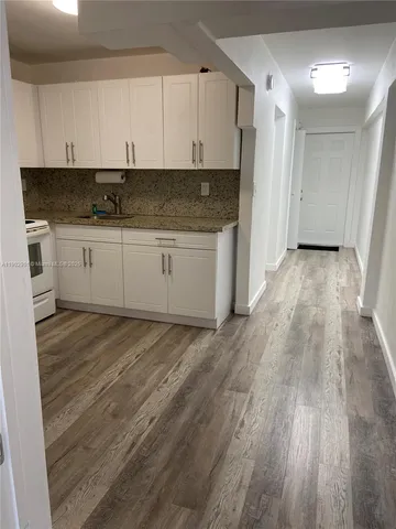 a view of kitchen with granite countertop white cabinets and stainless steel appliances