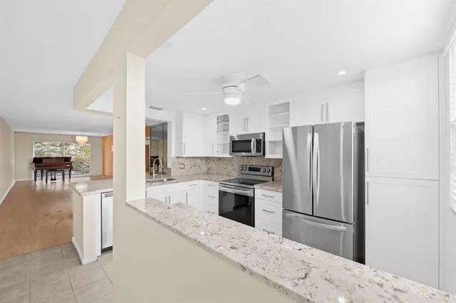 a kitchen with stainless steel appliances kitchen island granite countertop a refrigerator a stove a sink a oven with a dining table and chairs with wooden floor