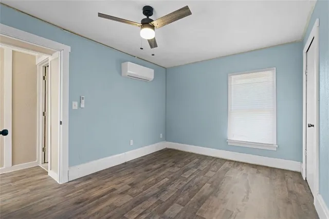 an empty room with wooden floor ceiling fan and windows