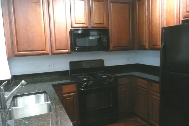 a kitchen with granite countertop white cabinets and black appliances