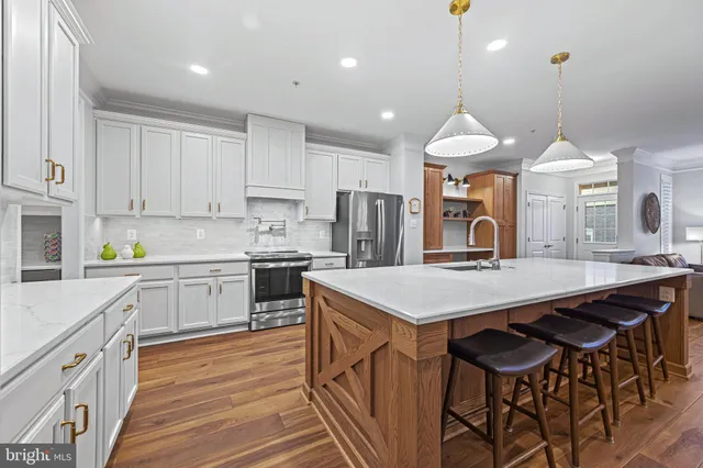 a kitchen with stainless steel appliances kitchen island a table chairs in it and wooden floors