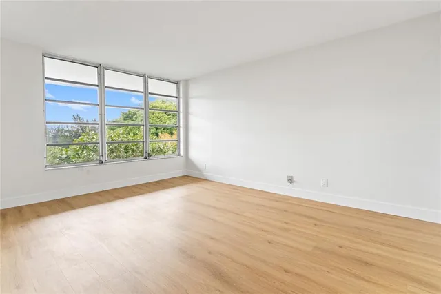 a view of an empty room with a window and wooden floor