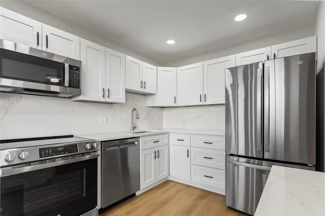a kitchen with stainless steel appliances a refrigerator sink and wooden floor
