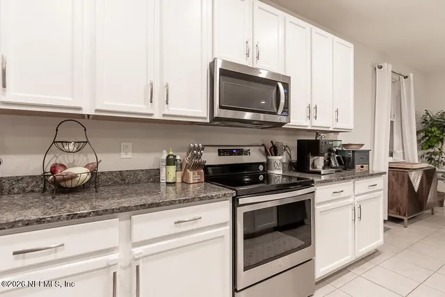 a kitchen with granite countertop white cabinets and white appliances
