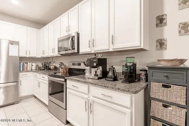 a kitchen with stainless steel appliances granite countertop a stove top oven a sink a microwave a dining table and chairs