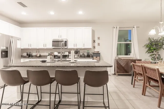 a kitchen with a dining table chairs and white cabinets