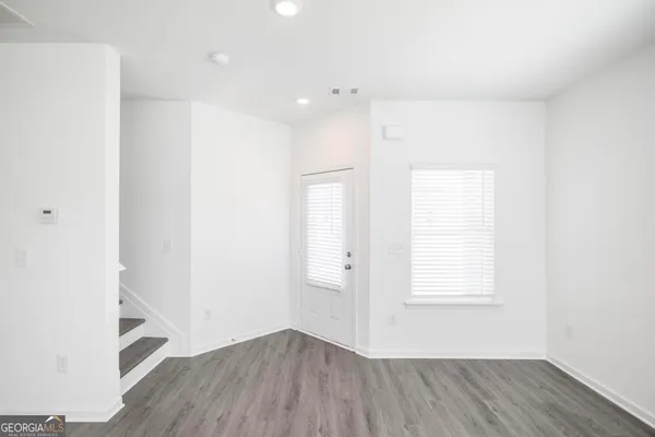 an empty room with wooden floor and windows