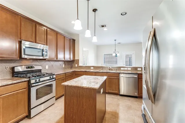 a kitchen with stainless steel appliances granite countertop a sink refrigerator and microwave