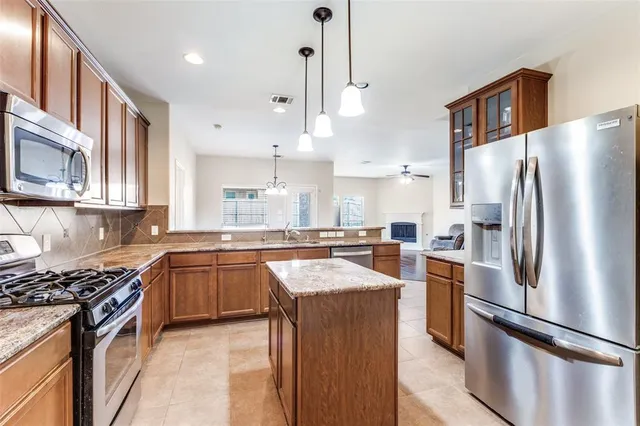 a kitchen with stainless steel appliances granite countertop a refrigerator a stove a sink and a microwave