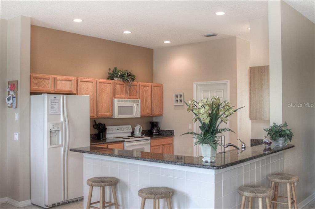 4418 Useppa Drive Bradenton, FL 34203 - Photo 7 of 22 a kitchen with white cabinets and a refrigerator