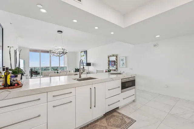 a large white kitchen with a sink and a stove top oven with wooden floor