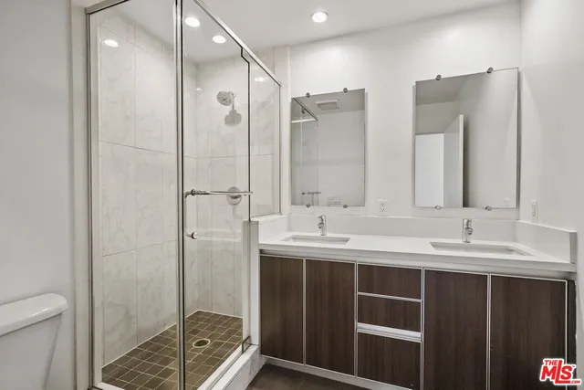 a bathroom with a double vanity sink mirror and shower